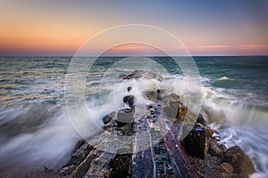 Waves and a jetty at sunset in the Atlantic Ocean at Edisto Beach, South Carolina.