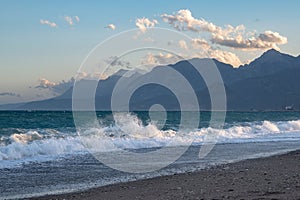 Waves on Konyaalti beach in Antalya with mountains covered in snow in the background