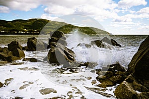 Waves of the Mediterranean Sea which with foam and splashes break against huge stones on the shore, Cagliari, Sardinia