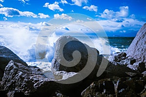 Waves of the Mediterranean Sea which with foam and splashes break against huge stones on the shore, Cagliari, Sardinia