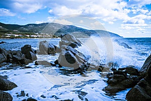 Waves of the Mediterranean Sea which with foam and splashes break against huge stones on the shore, Cagliari, Sardinia