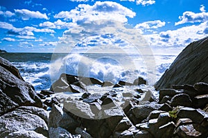 Waves of the Mediterranean Sea which with foam and splashes break against huge stones on the shore, Cagliari, Sardinia