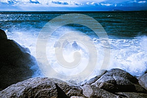 Waves of the Mediterranean Sea which with foam and splashes break against huge stones on the shore, Cagliari, Sardinia