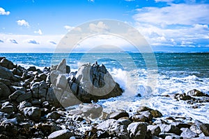 Waves of the Mediterranean Sea which with foam and splashes break against huge stones on the shore, Cagliari, Sardinia