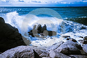 Waves of the Mediterranean Sea which with foam and splashes break against huge stones on the shore, Cagliari, Sardinia