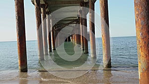 Waves are moving between the pillars of the sea pier. 4k steady shooting