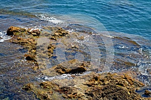 Waves in ocean break at rocky beach