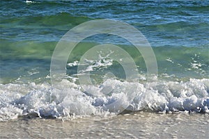 Waves from the ocean seethe and foam on the shore