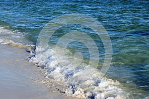 Waves from the ocean seethe and foam on the shore