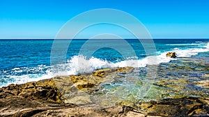 Waves of the Pacific Ocean crashing onto the rocky shoreline of the west coast of the island of Oahu