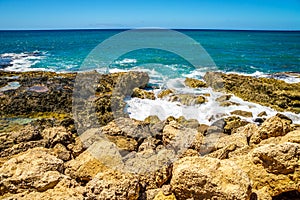 Waves of the Pacific Ocean crashing onto the rocky shoreline of the west coast of the island of Oahu