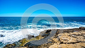 Waves of the Pacific Ocean crashing onto the rocky shoreline of the west coast of the island of Oahu