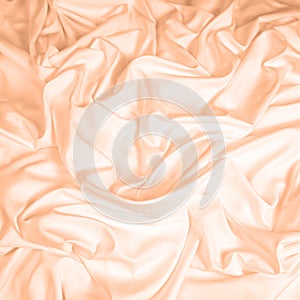 Waves and patterns of crumpled natural satin fabric. Color of the year 2024 Peach Fuzz