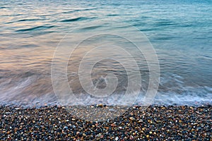 Waves on a pebble beach on a sunset.