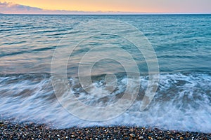 Waves on a pebble beach on a sunset.