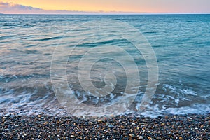 Waves on a pebble beach on a sunset.