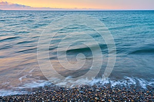 Waves on a pebble beach on a sunset.