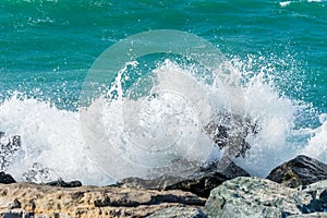 Waves of Persian Gulf splashing the stones of breakwater  at the crescent road in the Palm Jumeirah island in Dubai of the United