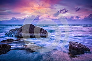 Waves and rocks on beach of sunset