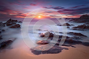 Waves and rocks in motion blur on coastline at dawn