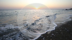 Waves roll on the seashore at sunset