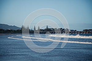 Waves rolling in on Coffs Harbour Beach with jetty in the distance