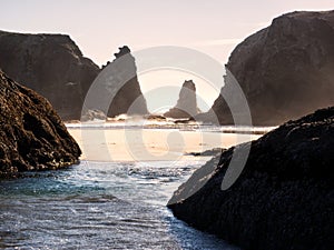 Waves on sandy beach with rock stacks photo