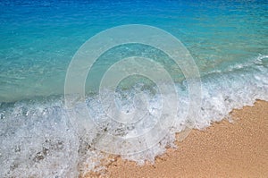 Waves and sea foam on the beach in Greece