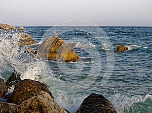 The waves of the sea surf are splashing against the stones of the shore