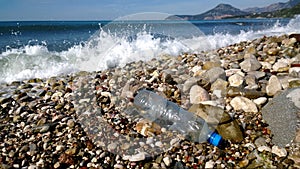 The waves of the sea washed up an empty plastic bottle. Environmental pollution - garbage in scenic spots