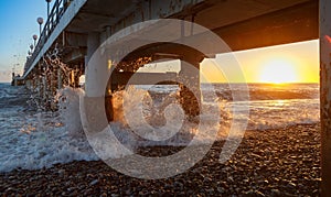Waves smite upon the pier support at sunset