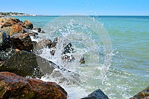 Waves splash on the large boulders on the beach