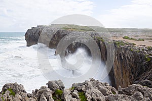 Waves splashing against the rocks of a cliff in Pria photo