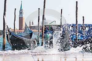 Waves splashing between parked gondolas in the Venetian lagoon