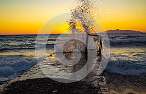 Waves splashing in a pier Aegean Sea Black beach sunrise view Santorini Greece