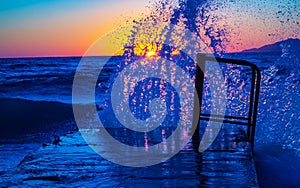 Waves splashing in a pier Aegean Sea Black beach sunrise view Santorini Greece