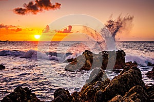 Waves splashing on rocks in the sunset. Sunset over the ocean with breaking waves. Rocks in the sea. Beautiful landscape of