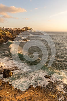 Waves splashing on the rocky shore in sunset light in tenerife los gigantes area