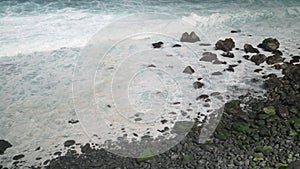 Waves are splashing to rocks in the sea and waves with foam.4k, flog. Foam from the strong water flow, Tenerife, Spain