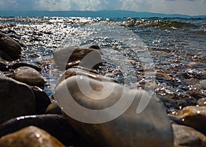Waves on a stone beach, the texture of the transparent clear waters of the lake