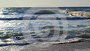 Waves of a stormy sea crashing against a pier on a sunny day