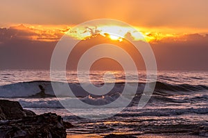 Waves with sunrise over storm clouds