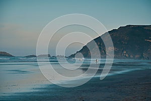 waves and surfers on a flat beach