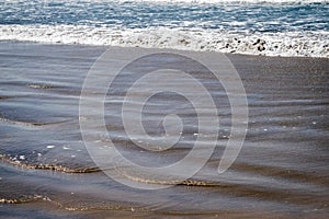 Waves surge onto the sandy beach.