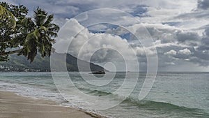 The waves of the turquoise ocean roll to the shore and foam on the beach.