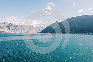 Waves on the turquoise sea at the foot of a high mountain range