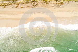 waves of a turquoise sea on the shore of a beach, aerial view with drone