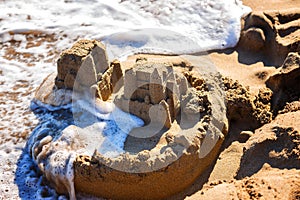 Waves wash away sand castles on beach the sea