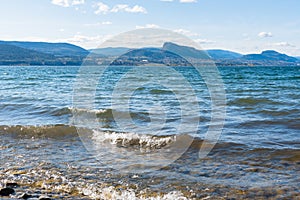 Waves washing onto Three Mile Beach at Okanagan Lake with view of Giant`s Head Mountain and blue sky photo