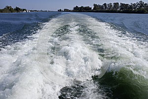 Waves and water stirred by the propellers of a ship`s engine as it advanced through a river, disturbing the animals